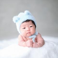 水色のくまのニット帽をかぶった赤ちゃんの写真