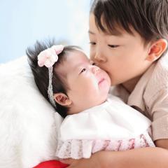 赤ちゃんにキスをするお兄ちゃんの写真