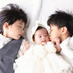 寝転んで妹にキスをする兄たちの写真