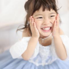 頬を包んで笑っているおんなのこ