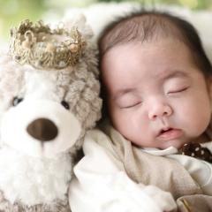 クマのぬいぐるみと眠っているあかちゃん