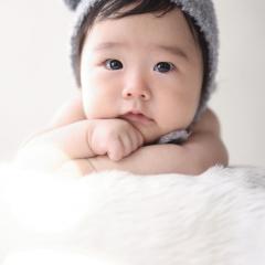 熊のかぶりものを付けてうつ伏せをする赤ちゃん