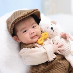 タキシードを着てクマのぬいぐるみをもっているあかちゃん