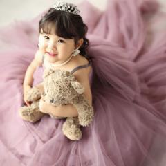 紫のドレスを着てクマのぬいぐるみを持っているおんなのこ
