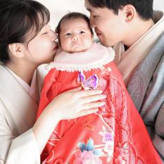 着物を着たあかちゃんにキスをする両親