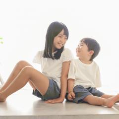 私服で背中を合わせて座るきょうだい