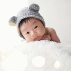 くまの被り物をしてうつぶせをするあかちゃん