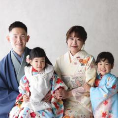 青い振袖を着て家族と記念撮影をする姉妹