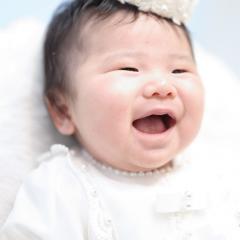 白いドレスを着て笑ってる赤ちゃん