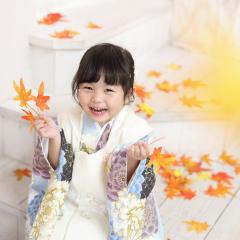 もみじを持って笑顔で写真を撮ってる女の子